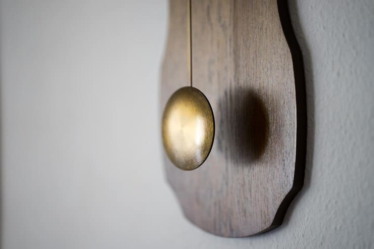 antique-metallic-pendulum-against-wall